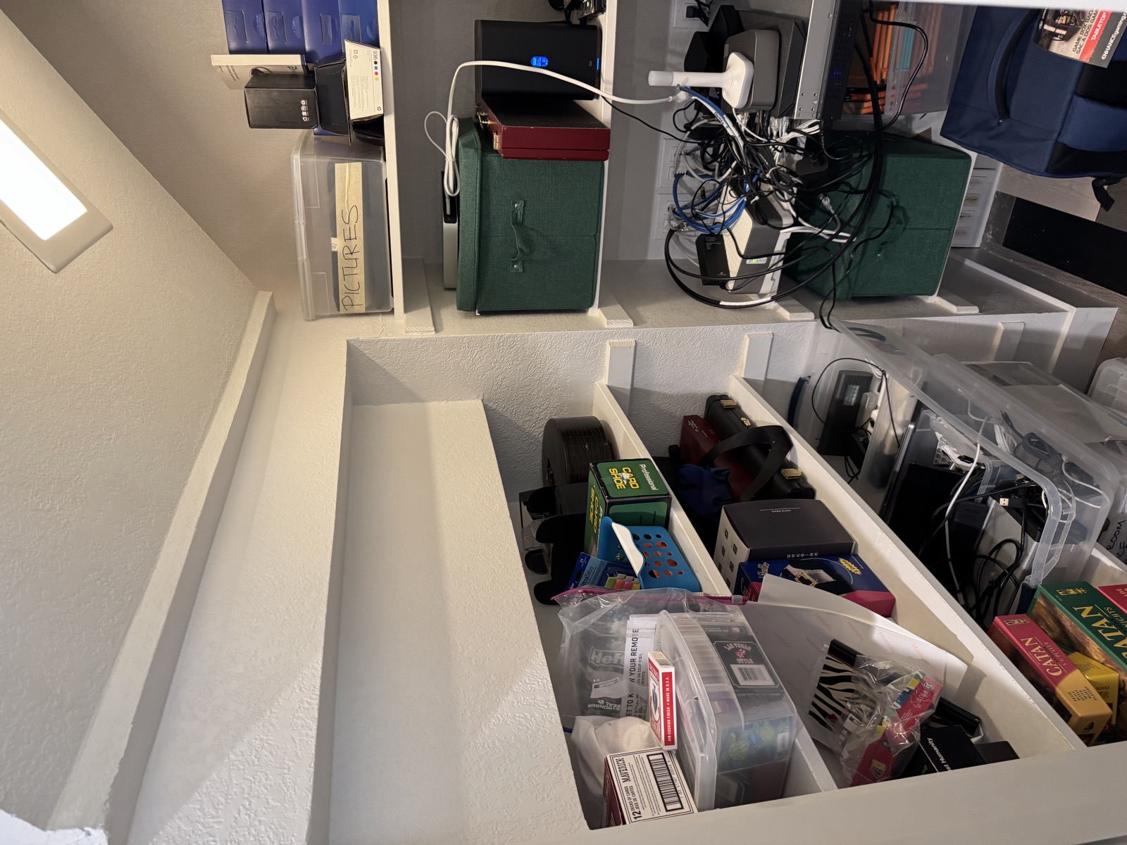 Looking into the closet from the doorway: the left shelf wall under the sloped ceiling, and the narrow back bay with the network gear on the right